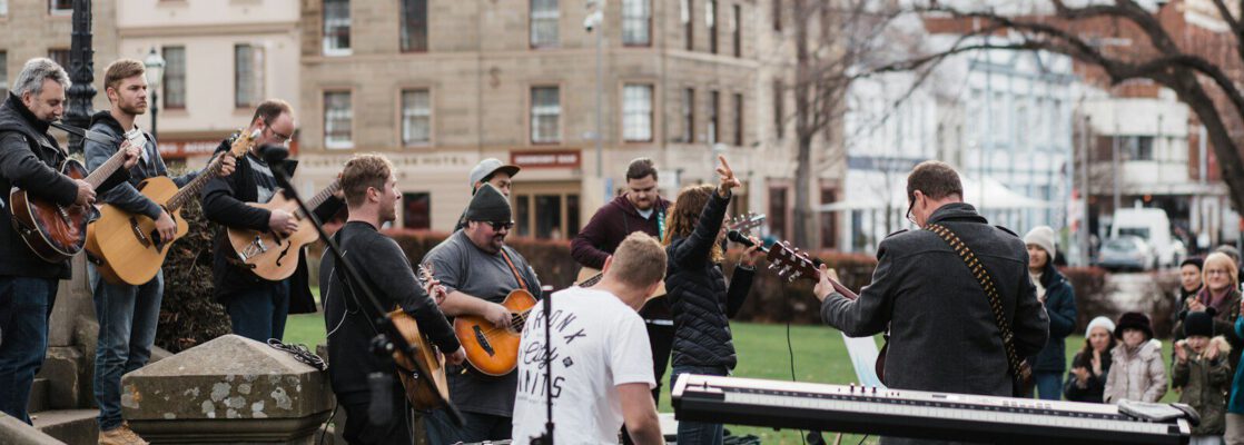 man in blue long sleeve shirt playing electric guitar