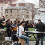man in blue long sleeve shirt playing electric guitar