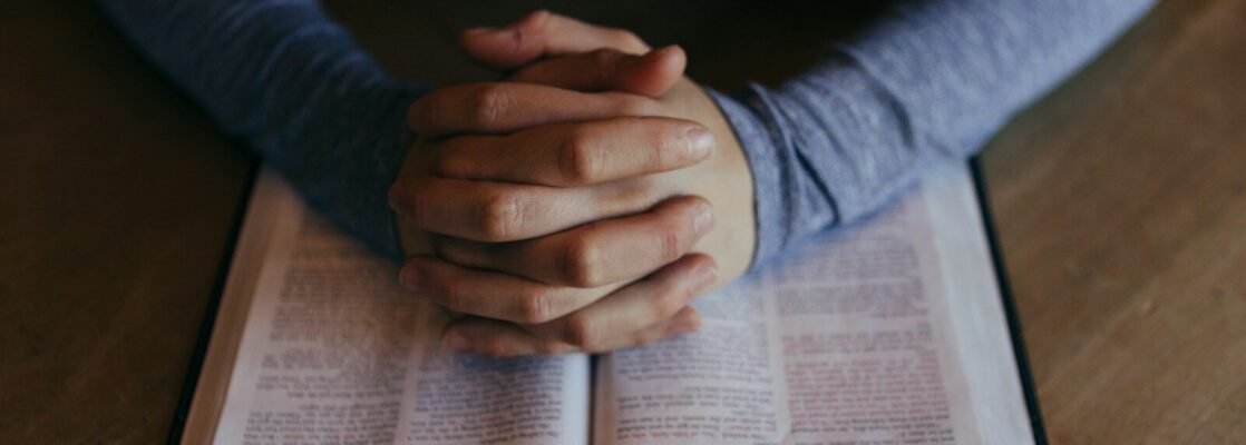man holding his hands on open book