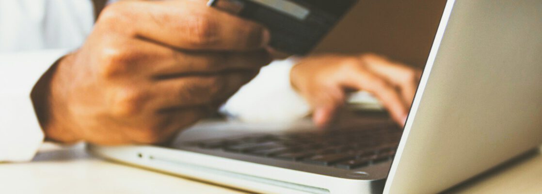 person using laptop computer holding card